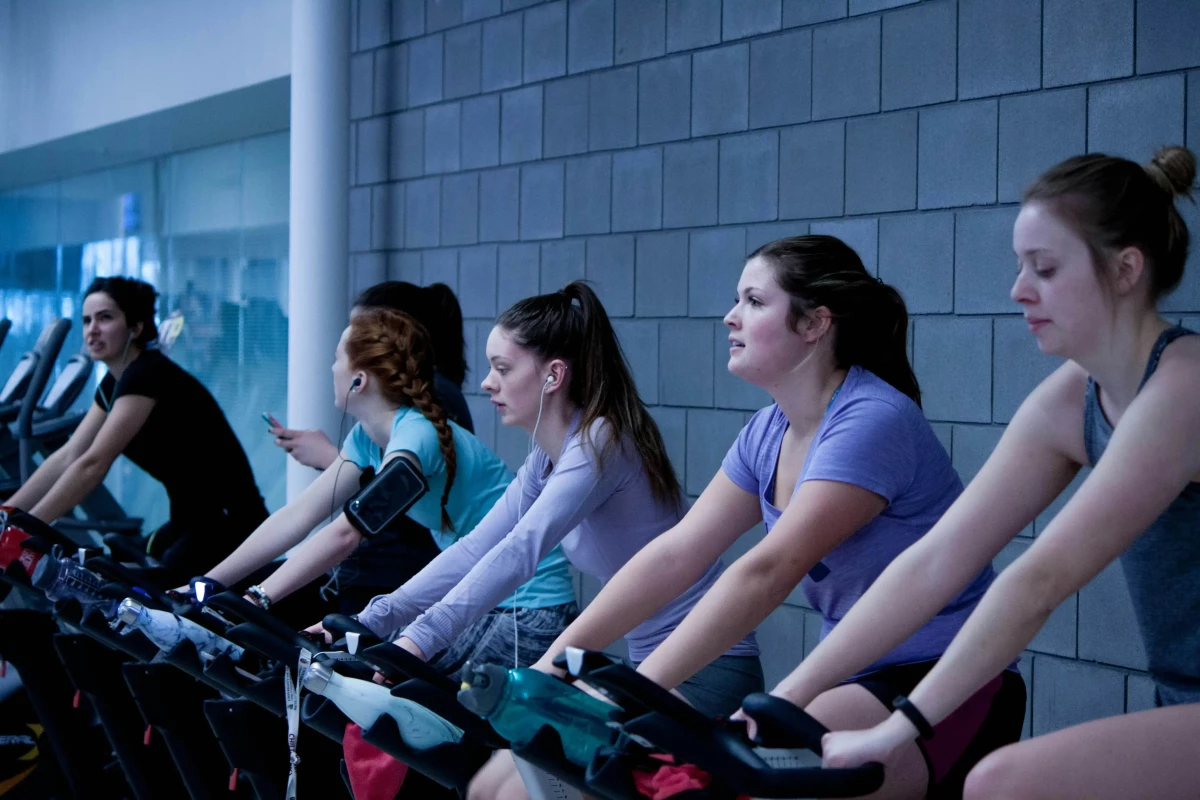 Group of women on exercise bycicles in the gym
