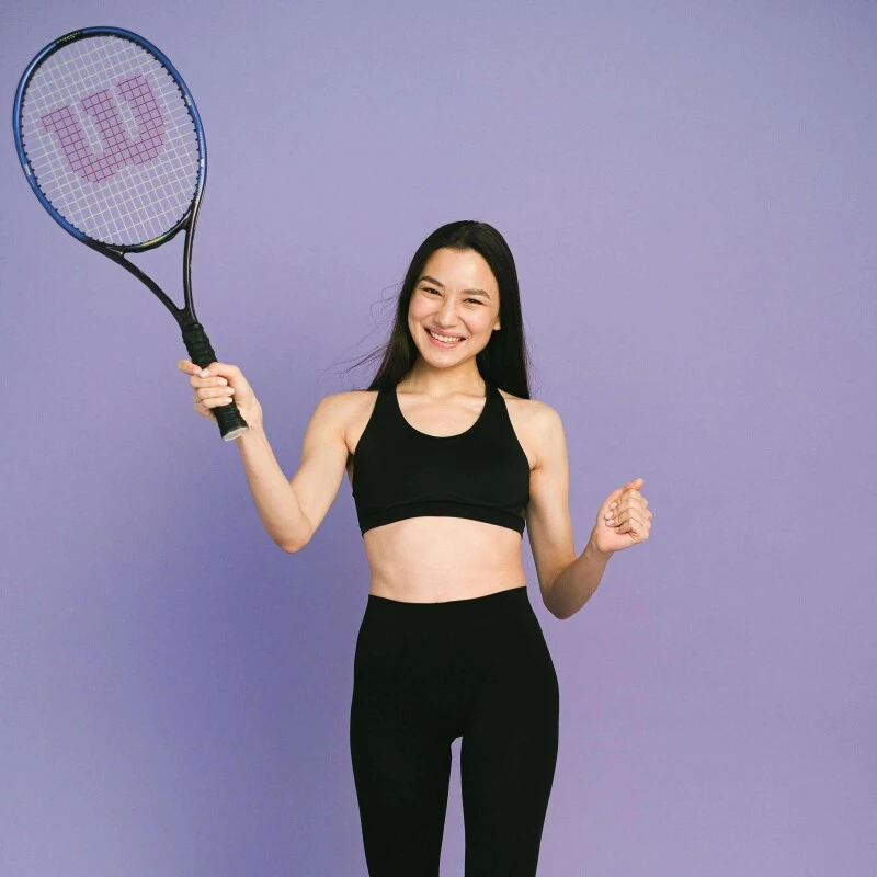 Young woman in sports bra and leggins with a tennis racket