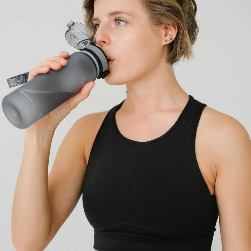 Young woman in sports bra drink from a drinks bottle